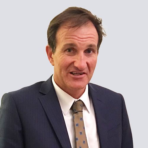 A man in a suit and tie is smiling for the camera