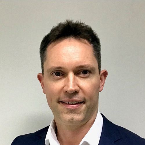 A man in a suit and white shirt is smiling for the camera.