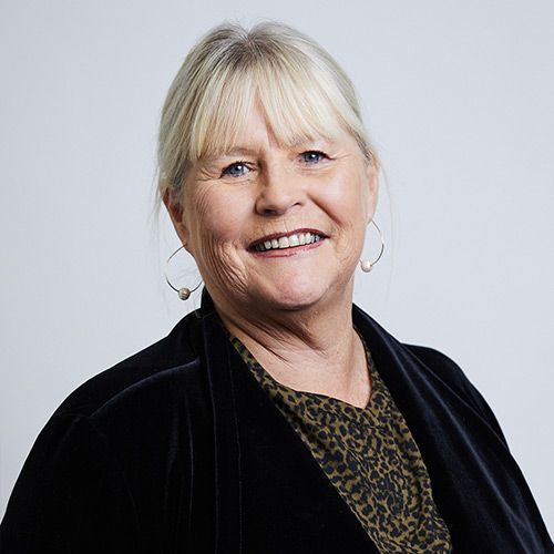 A woman wearing a black jacket and leopard print shirt is smiling for the camera.
