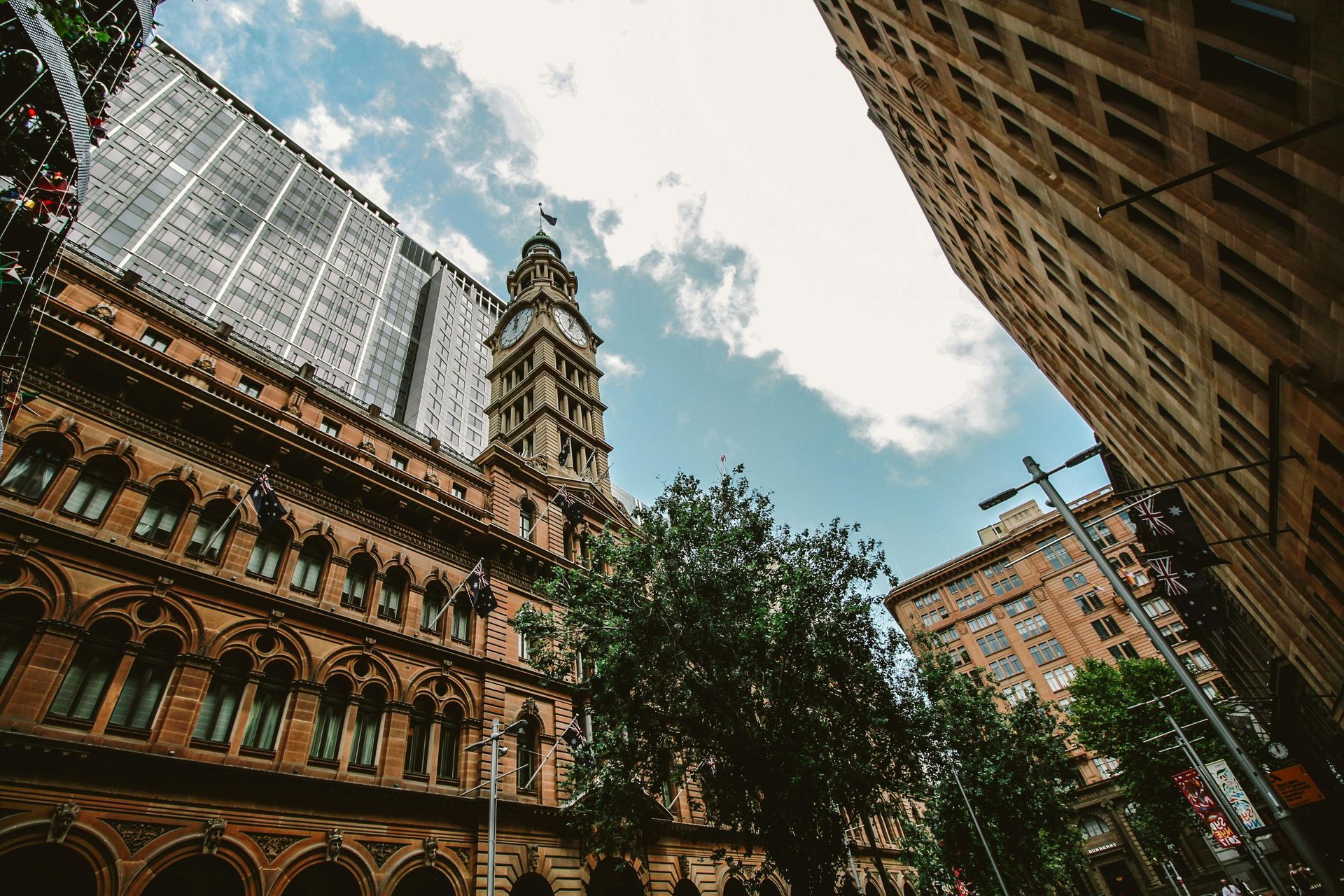 Looking up at a building with a clock tower in the middle of a city.