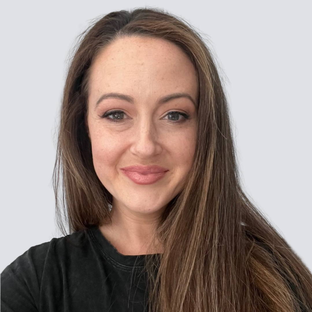 A woman with long brown hair is smiling and wearing a black shirt.