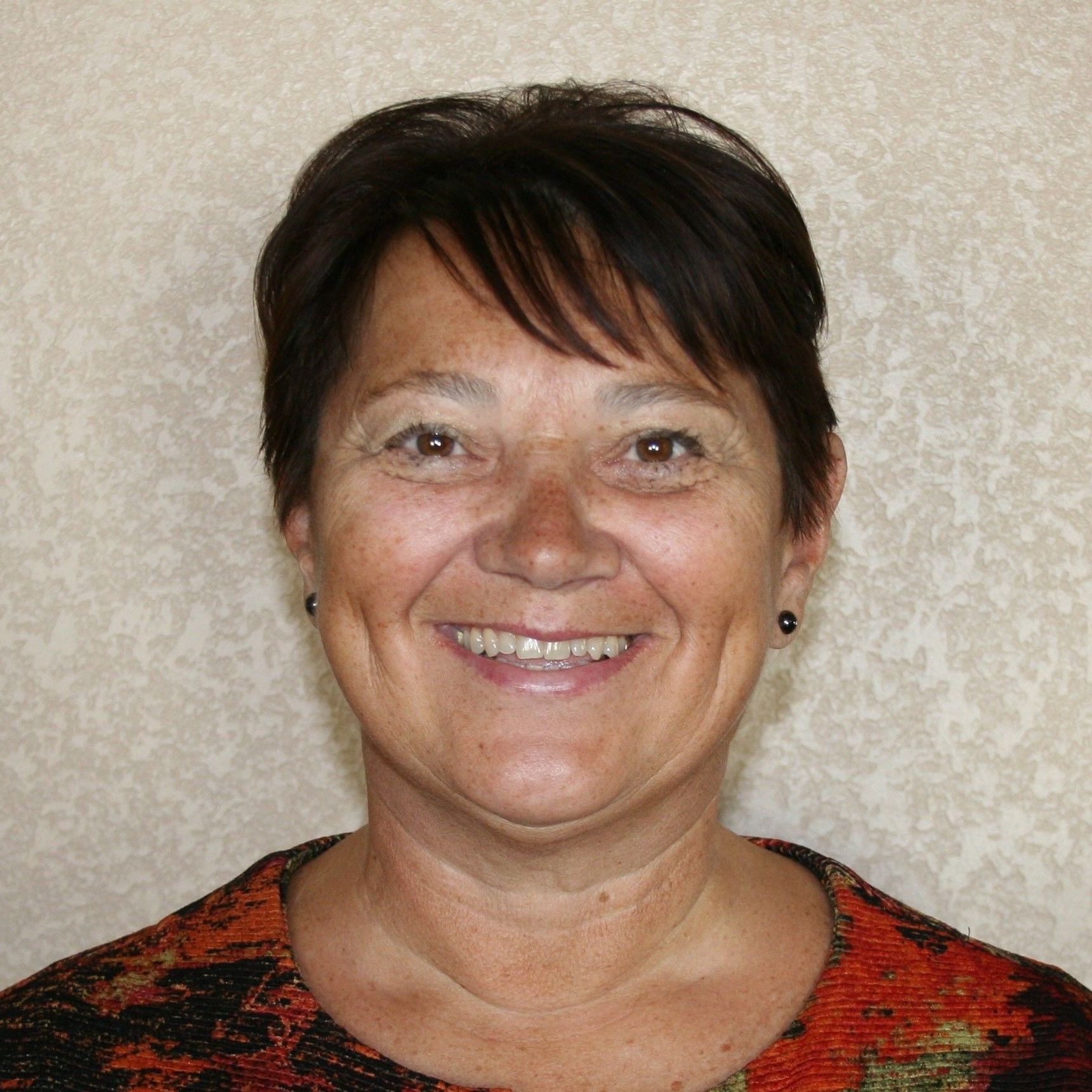 A woman in an orange shirt is smiling for the camera