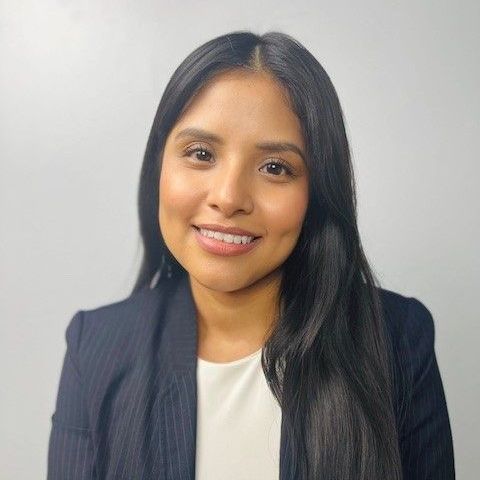 A woman in a suit and white shirt is smiling for the camera.