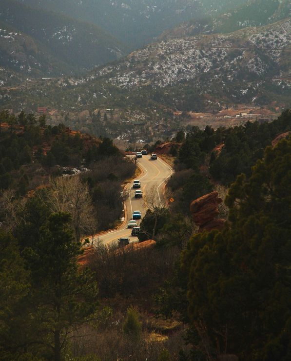 Cars are driving down a road in the mountains