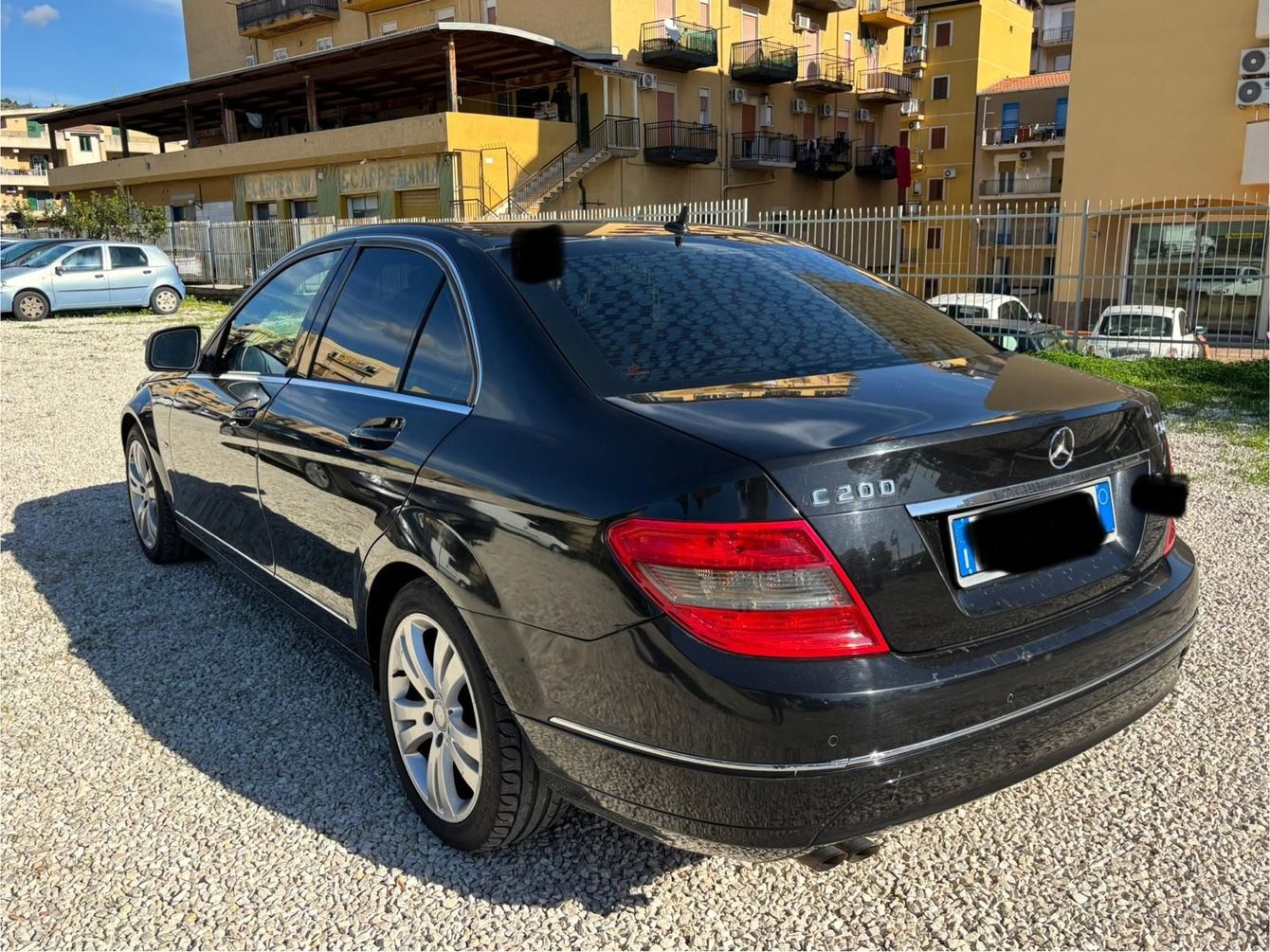 Una berlina di lusso nera è parcheggiata davanti all'ingresso di un hotel, con ospiti in abito formale che arrivano al crepuscolo.