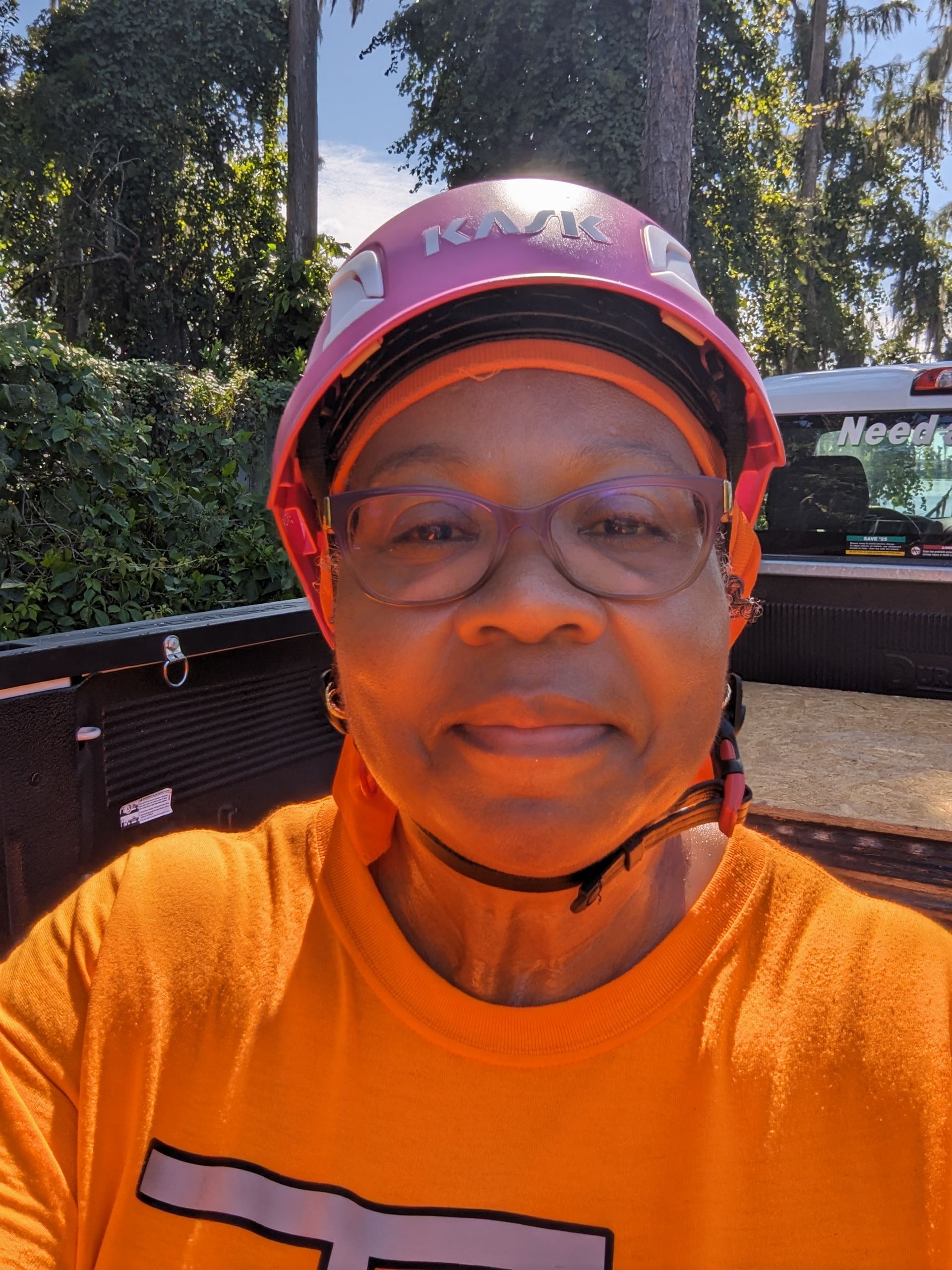 A woman wearing a hard hat and glasses is taking a selfie.