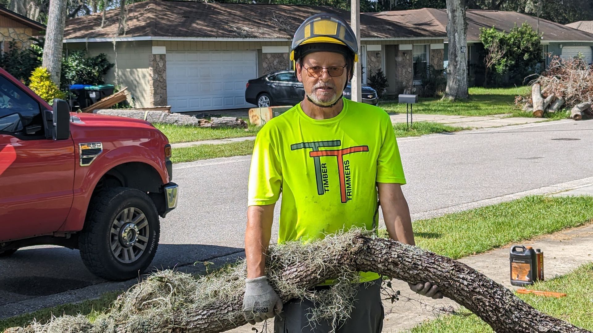 A man is holding a large piece of wood in front of a red truck.