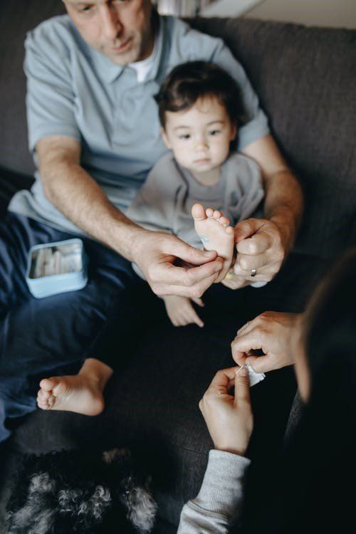 a couple putting a band-aid on their child's foot