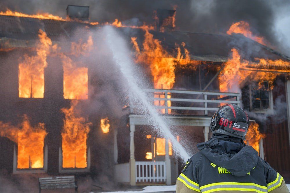 A firefighter using a hose on a burning building