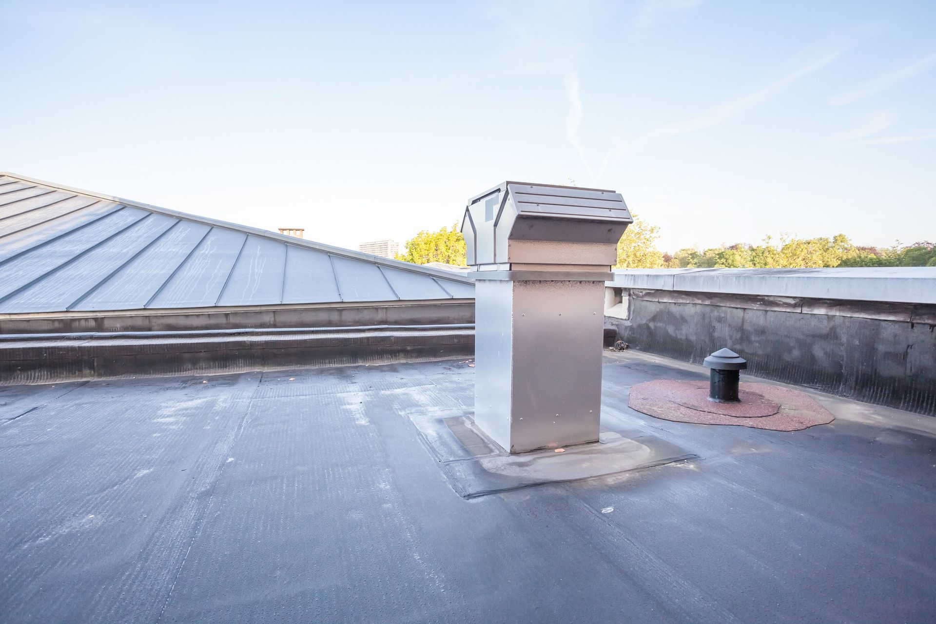 Flat roof with a venting pipe. The ground in that area is darker thanks to the rain.