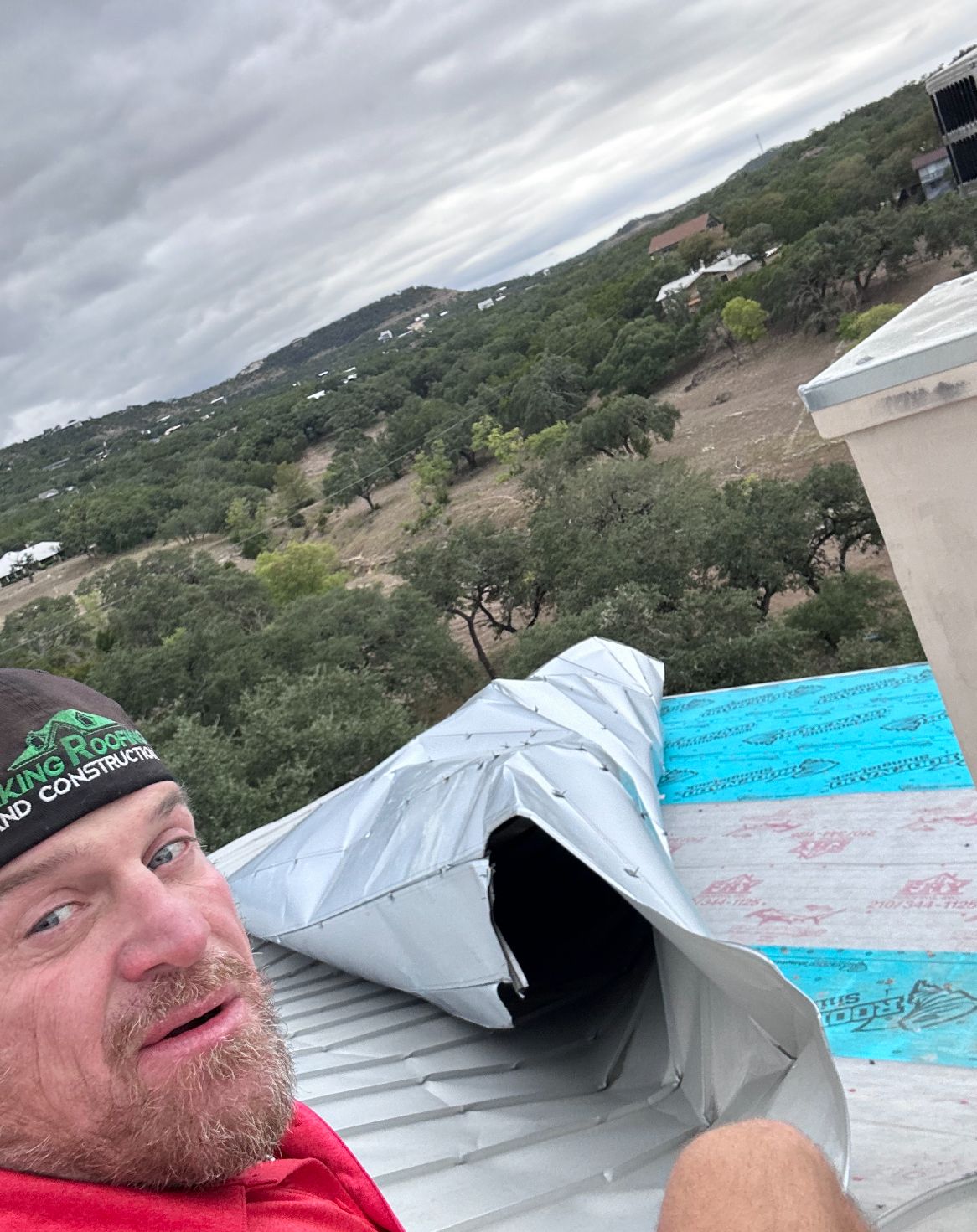 A man is sitting on top of a metal roof.