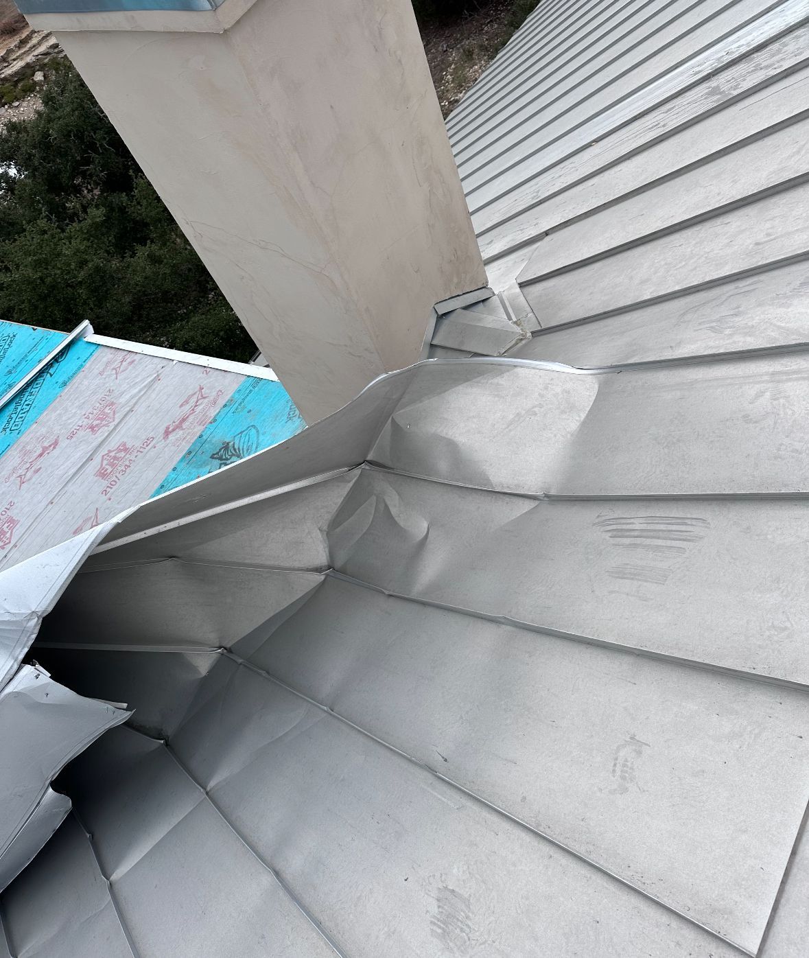 A close up of a roof with a chimney in the background