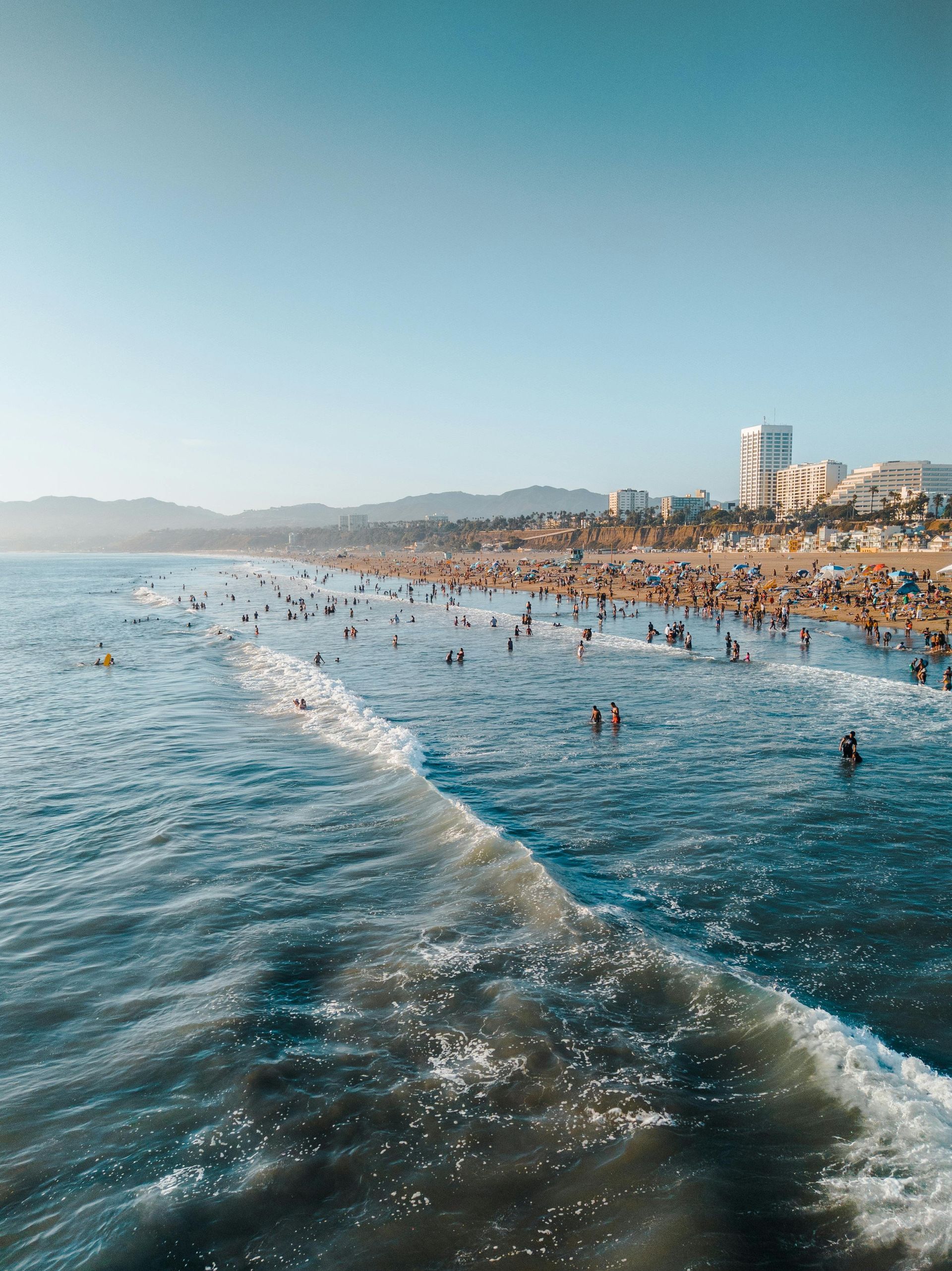 A group of people are swimming in the ocean near a beach.