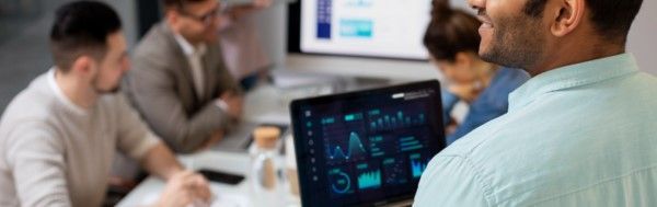 Equipe de profissionais de TI em ambiente corporativo, analisando gráficos e dados durante implementação de sistema.