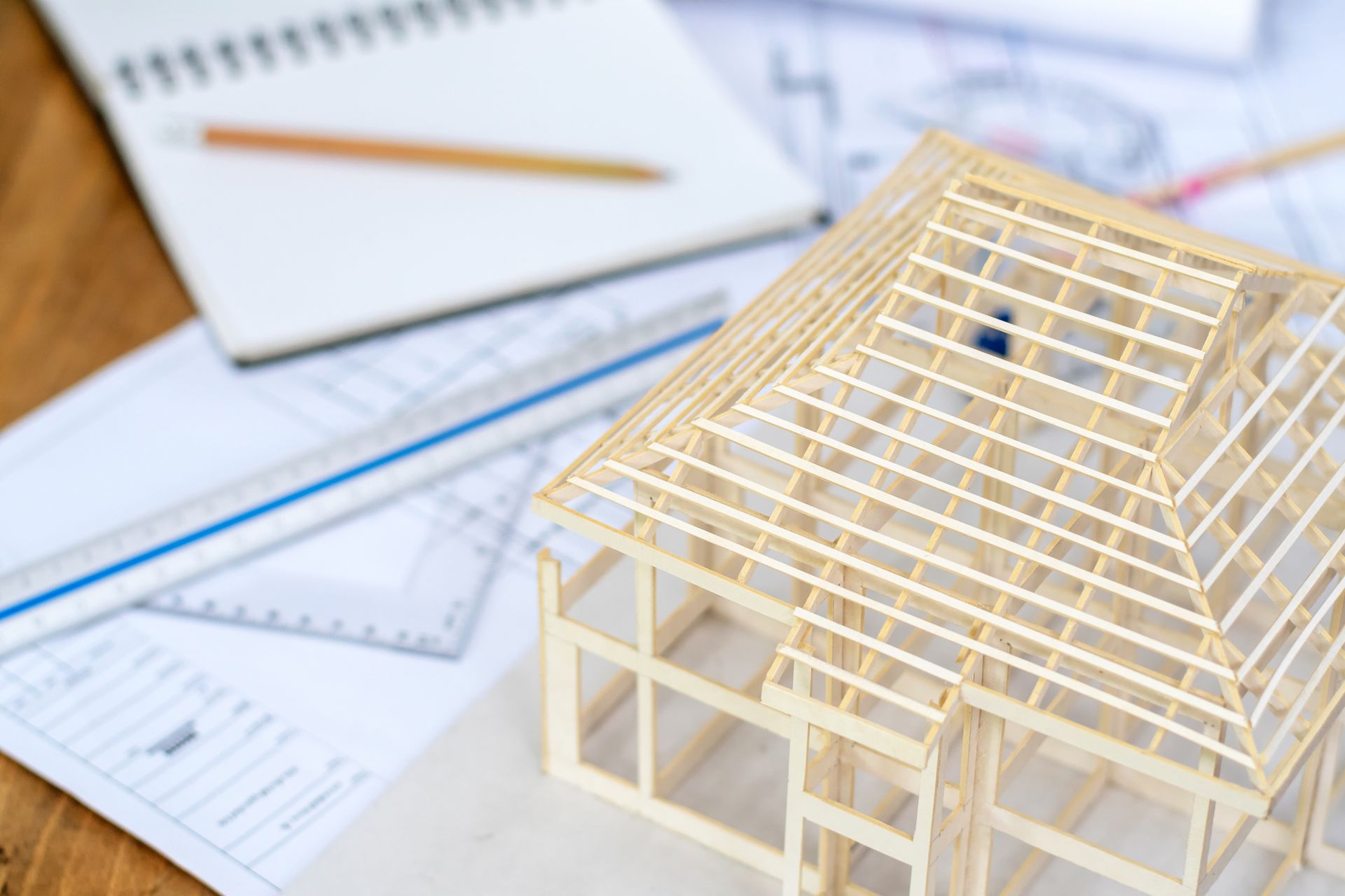 Modello di struttura di una casa su progetti con righello, quaderno e matita.