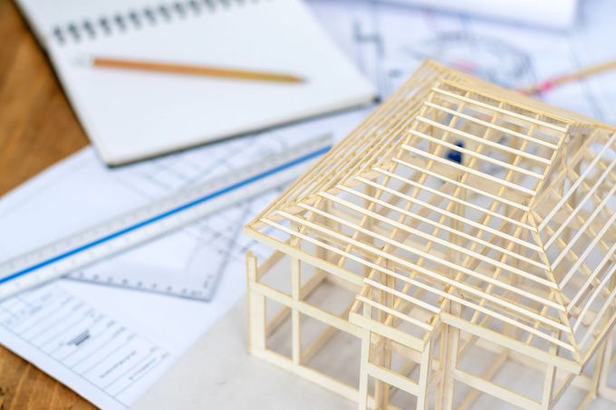 Modello di struttura di una casa su progetti con righello, quaderno e matita.