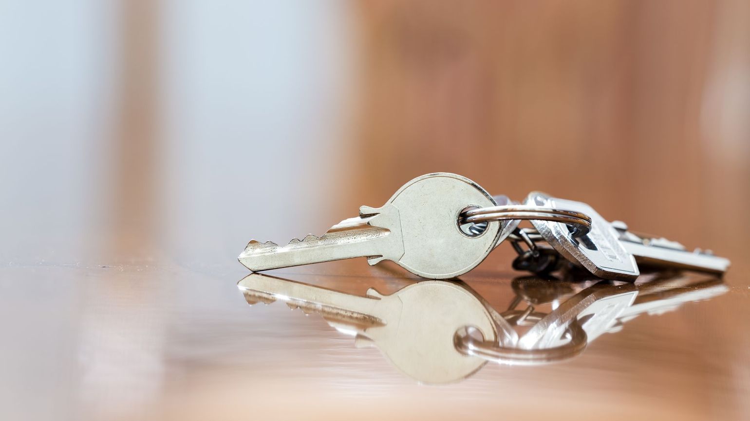 Keys resting on a reflective, wooden surface.