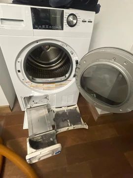 A washing machine and dryer are sitting on a wooden floor with the door open.