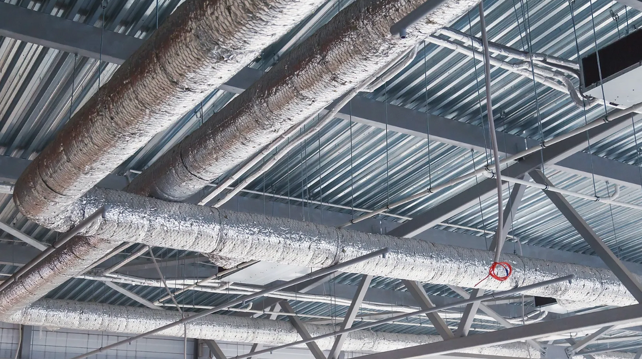 A bunch of pipes are hanging from the ceiling of a building.