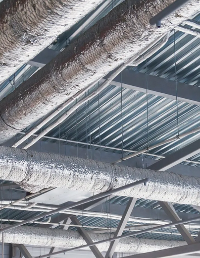 The ceiling of a building with a lot of pipes hanging from it.