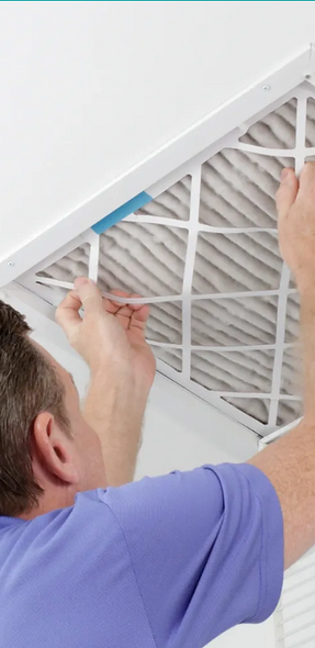 A man is cleaning an air filter with a brush.