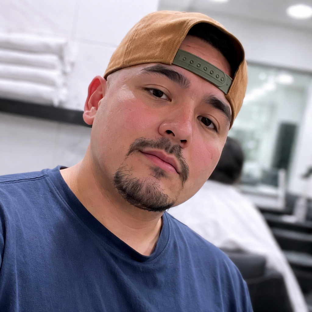 Man in blue shirt and brown cap looks at the camera.