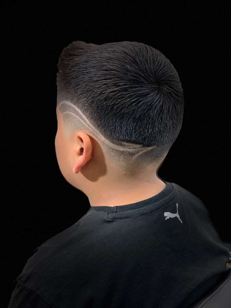 Barber shop tools in an open drawer, including clippers, scissors, and a hand with a brush.