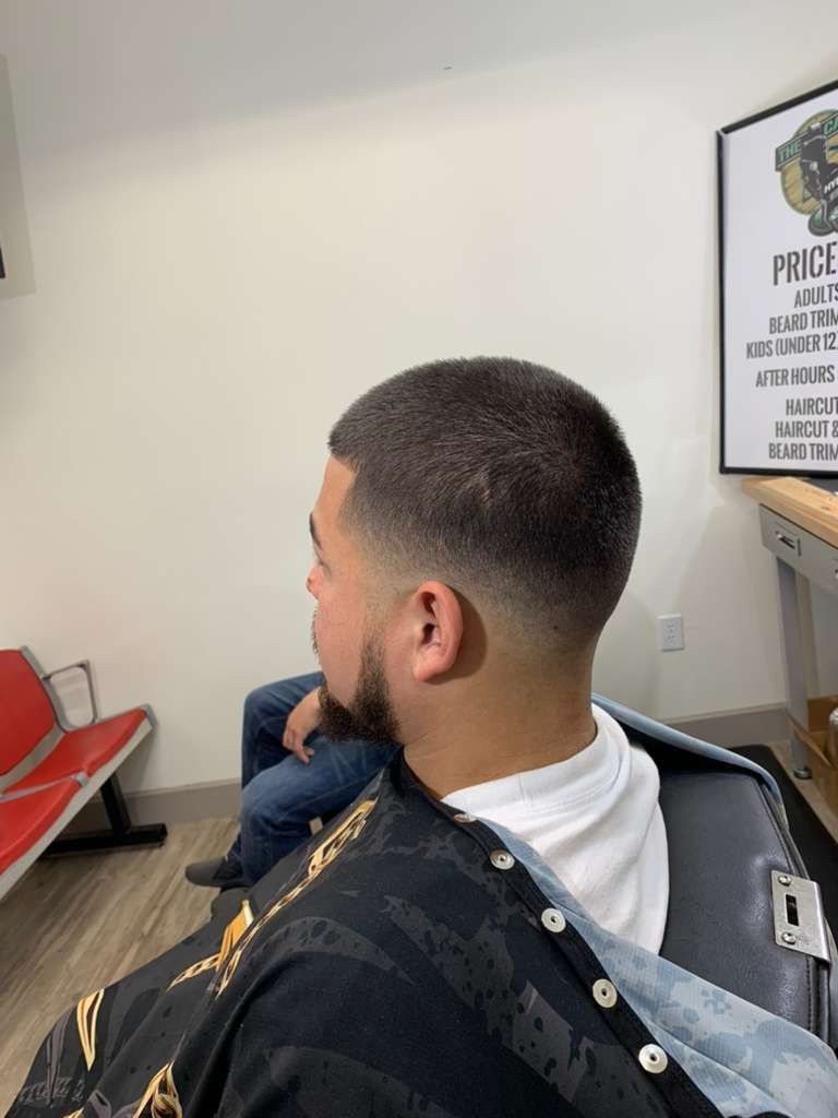 Man in barber chair with faded haircut, seated in a barbershop.