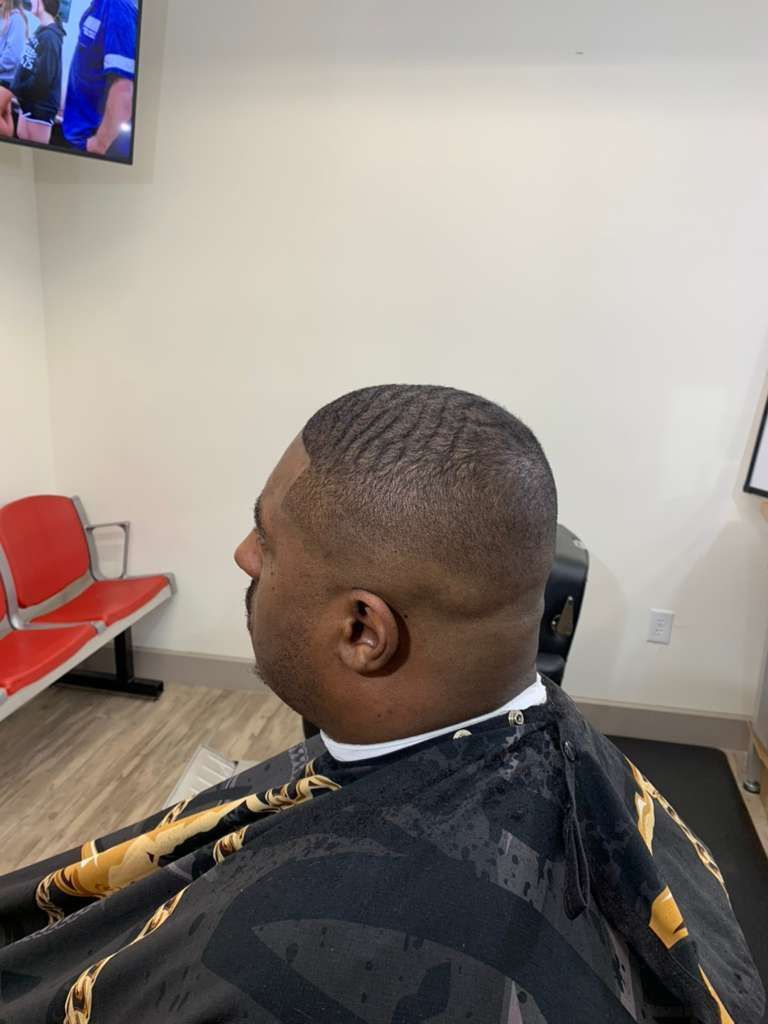 Man getting a haircut in a barber shop, with waves on top and a low fade.