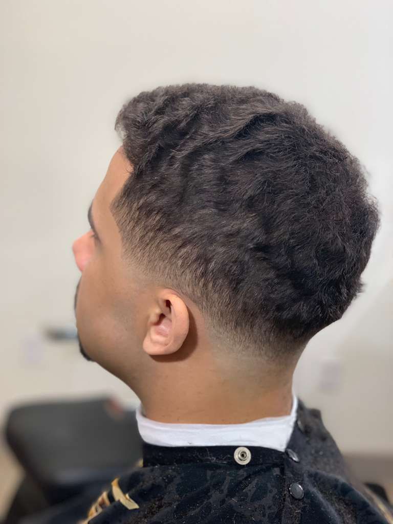 Man with dark hair, a fade haircut, and a beard, seen from the side.