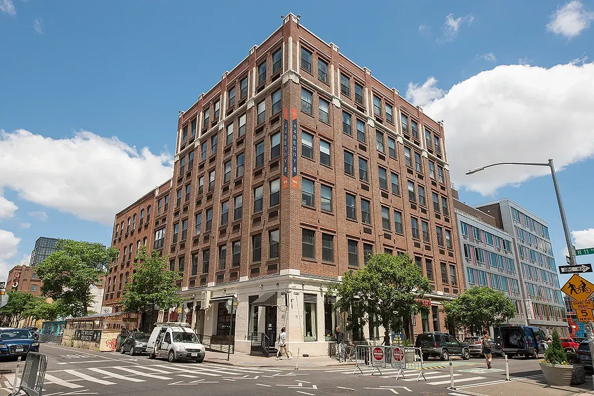 A large brick building is sitting on the corner of a city street.