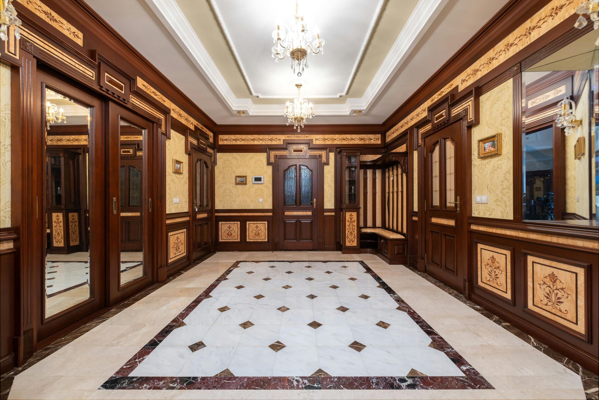 Hallway with ornate wood paneling, decorative floor, and mirrored doors.