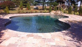 Pool with dark water, surrounded by stone patio.