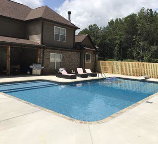 A house with a backyard pool and lounge chairs. 
