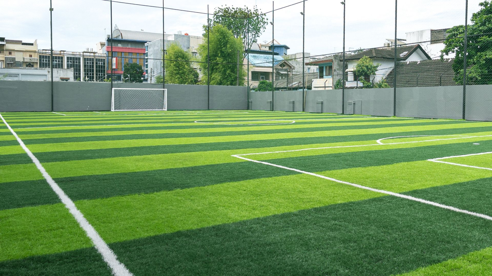 Empty green soccer field with white lines and goal under a bright sky