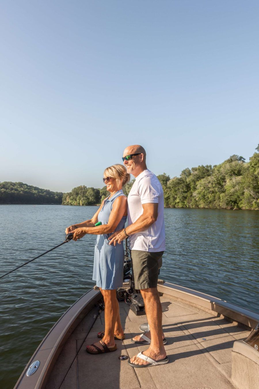 A man and a woman are fishing on a boat on a lake.