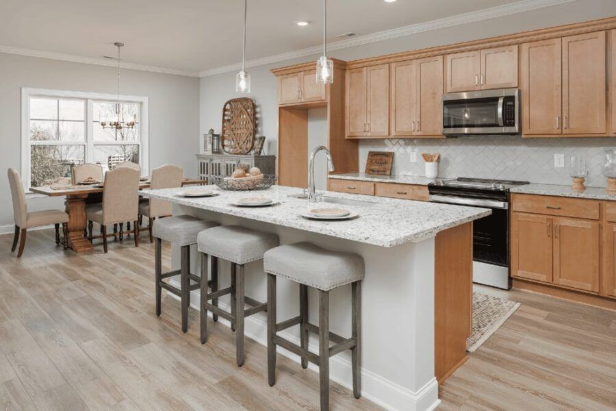 A kitchen with a large island in the middle and a dining room in the background.