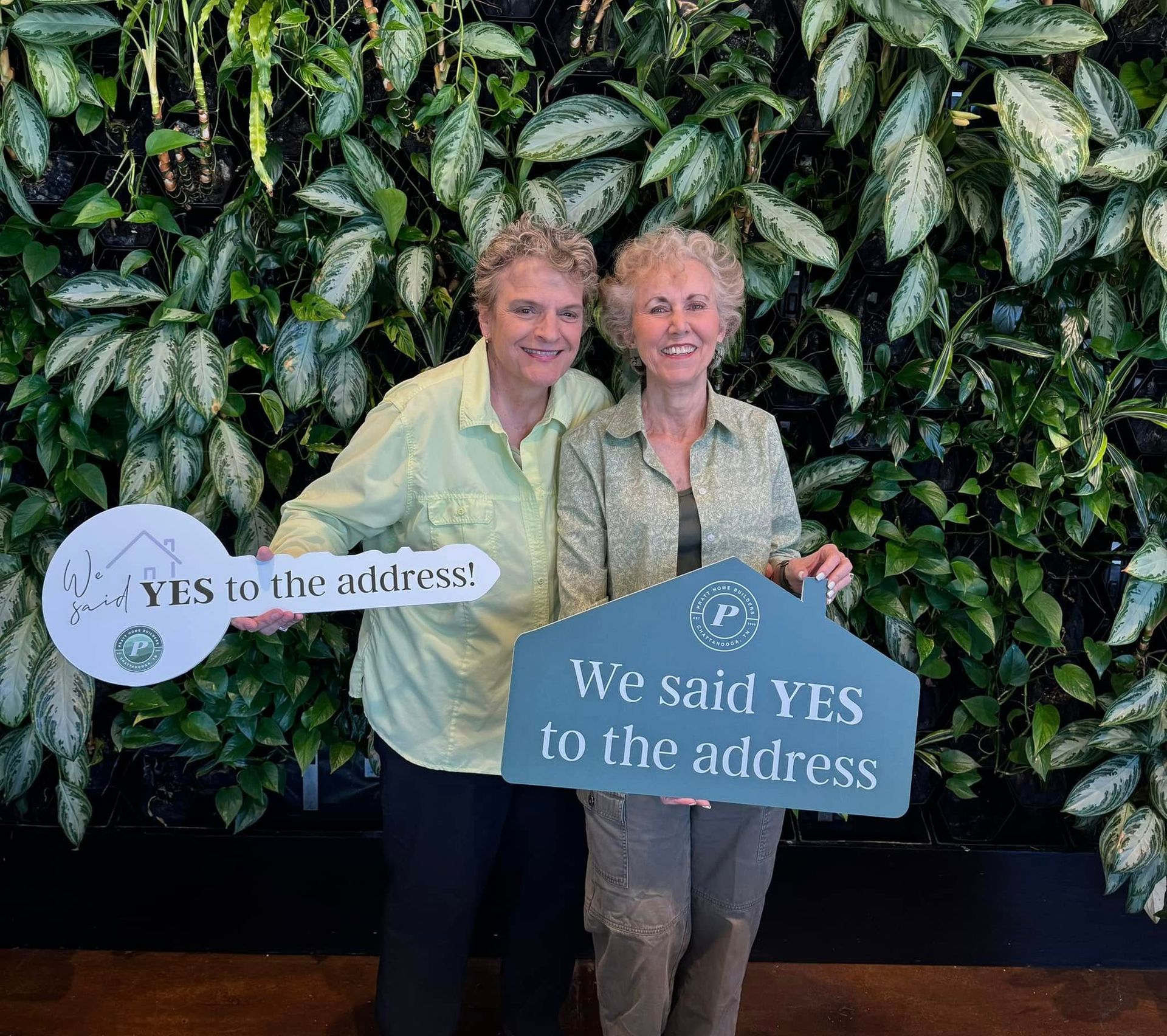 Two women holding signs that say yes to the address