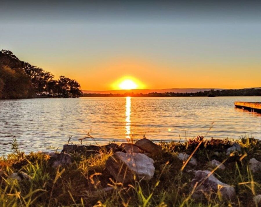 A sunset over a lake with a dock in the distance