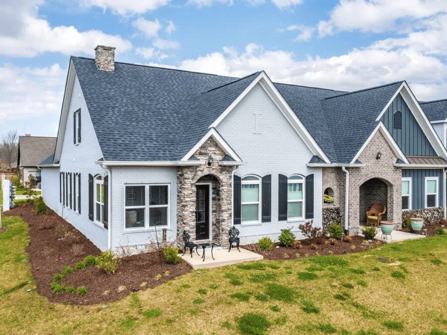 A white house with a blue roof is sitting on top of a lush green field.