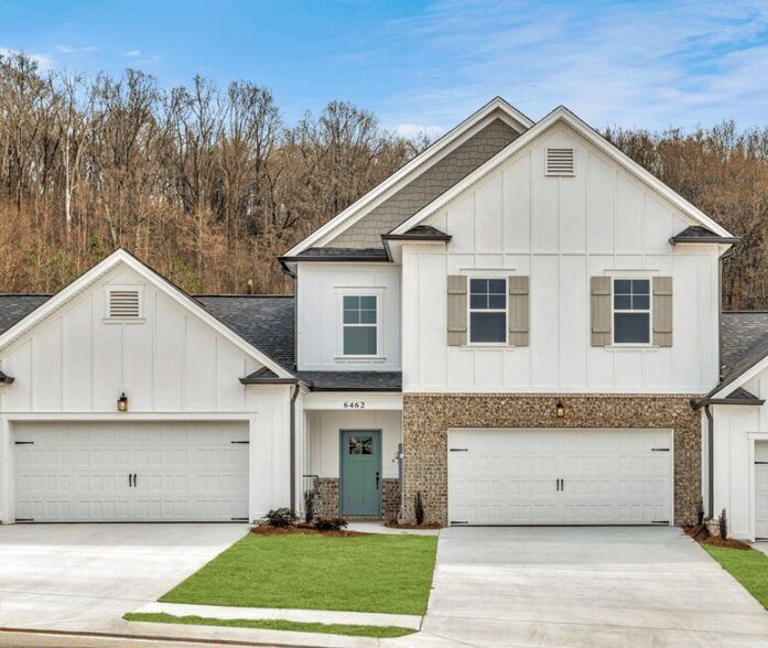 A large white house with two garages and a blue door