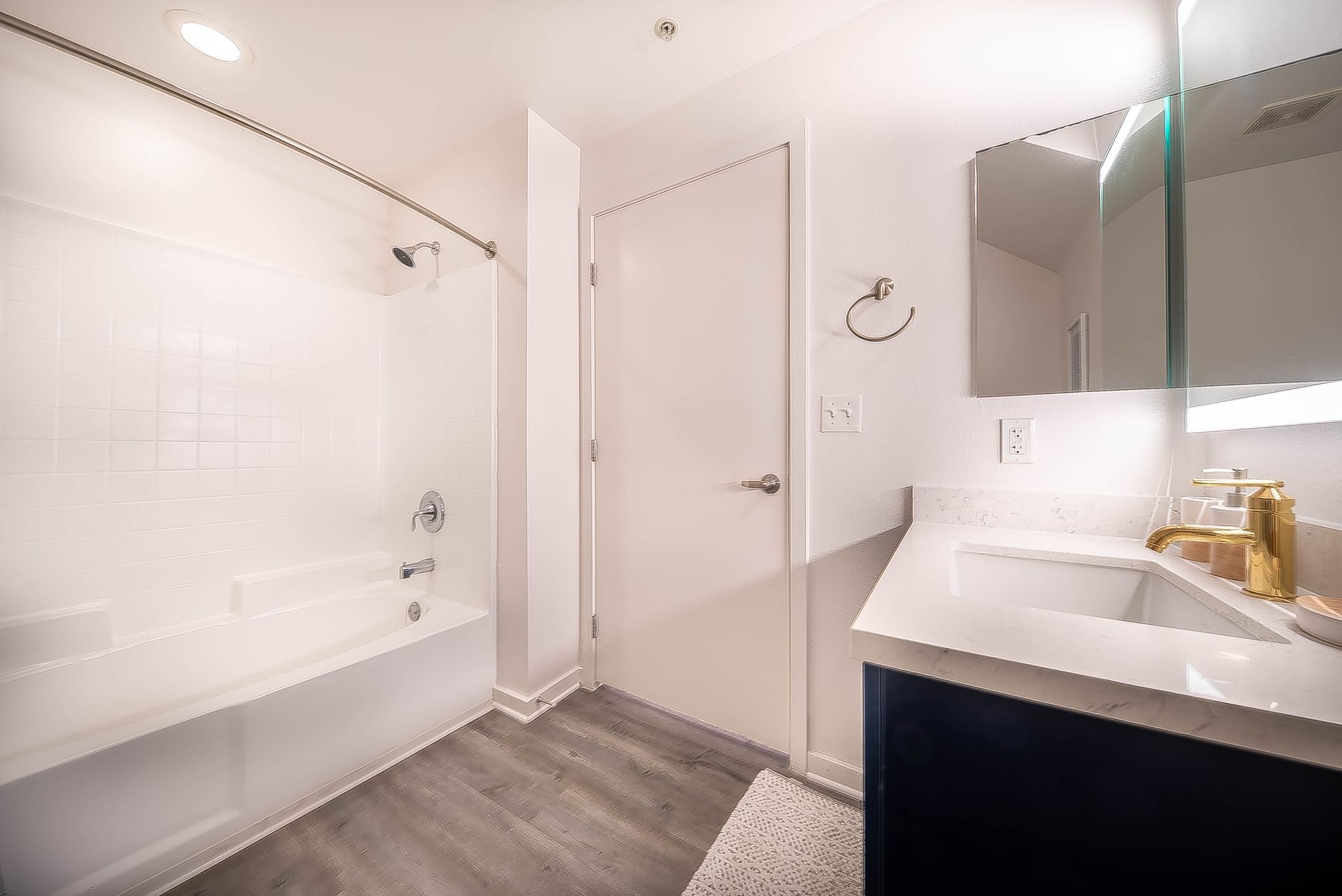 A bathroom with a sink , tub , shower and mirror.