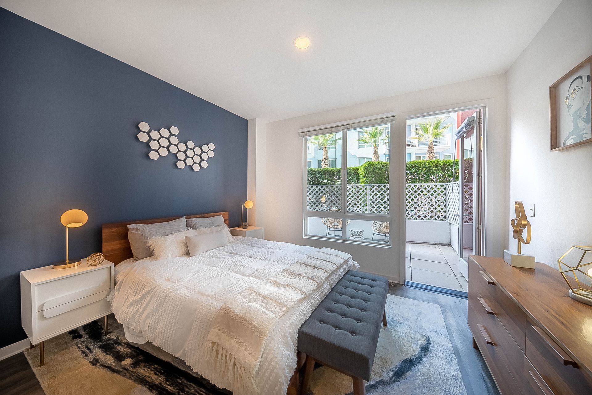 A bedroom with a bed , dresser , nightstand , and bench.