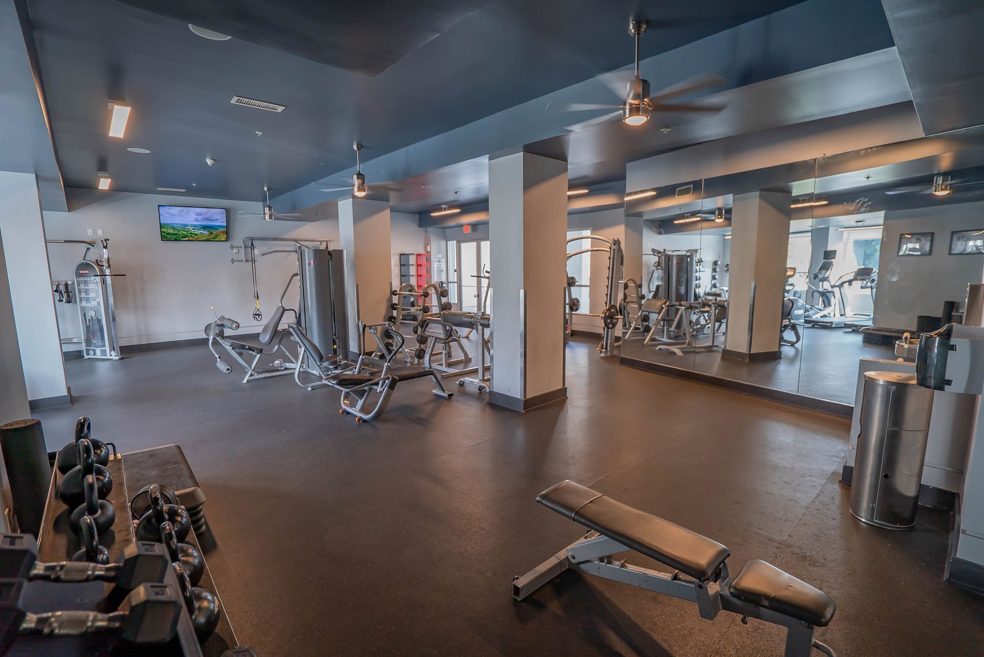 A large gym filled with lots of exercise equipment and a bench.