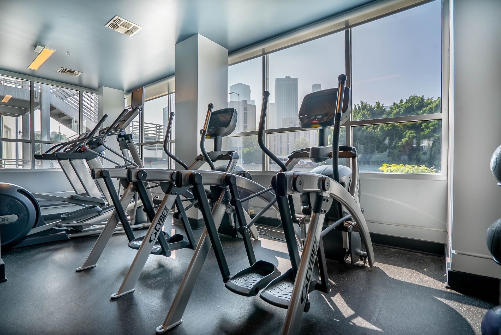 A gym with a lot of exercise equipment and a large window.