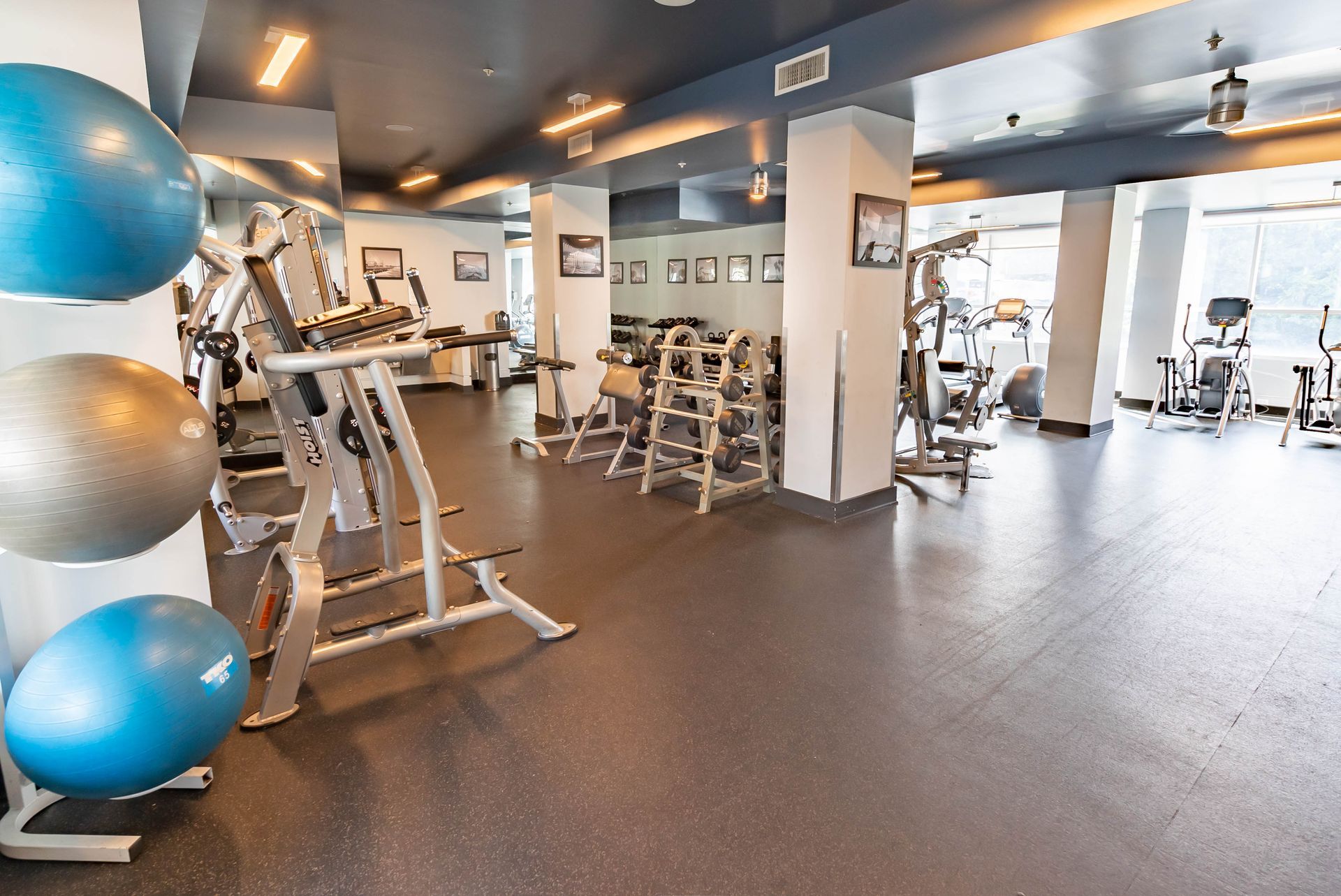 A gym with a lot of equipment and balls on the floor