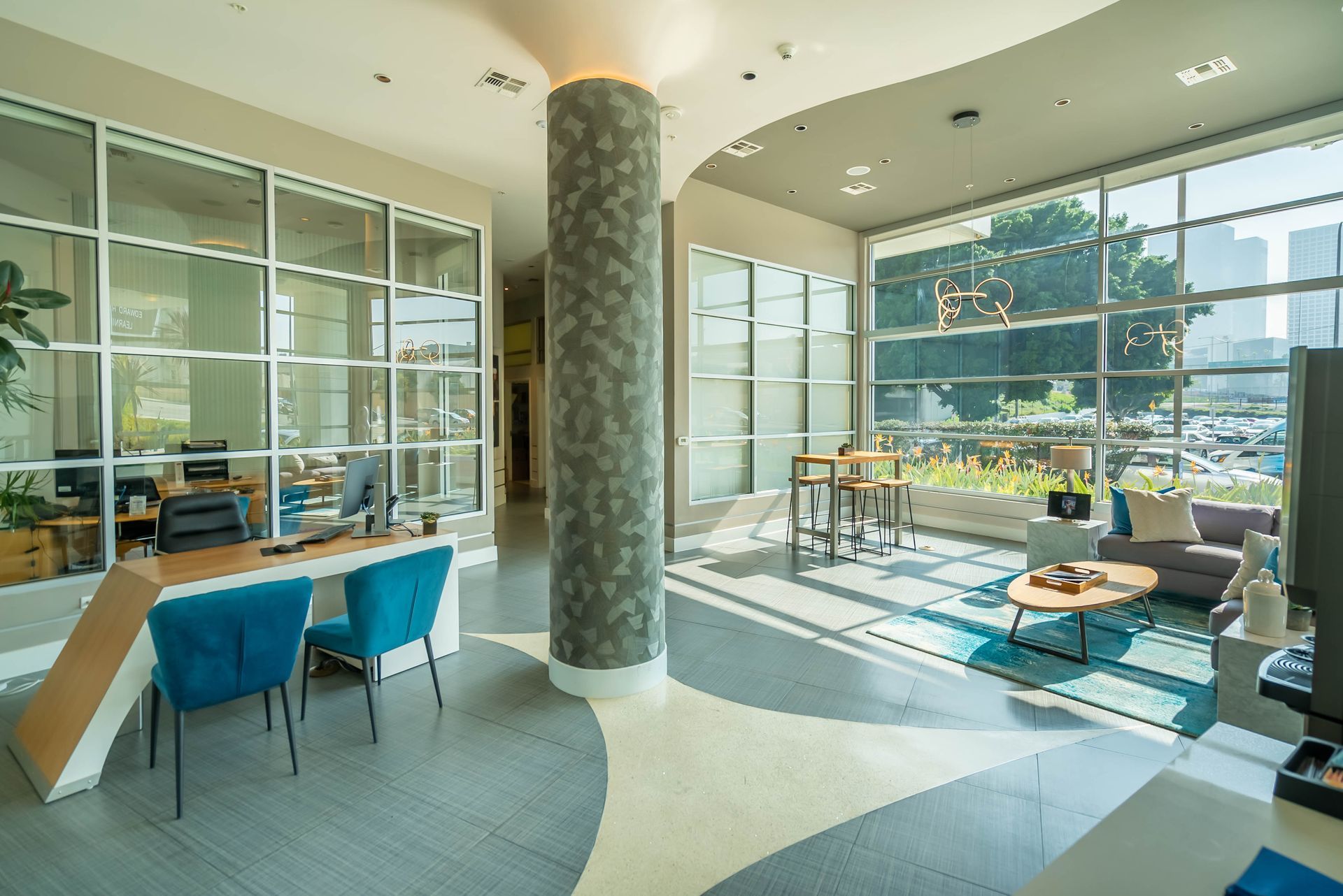 A lobby with a desk , chairs , a couch and a lot of windows.