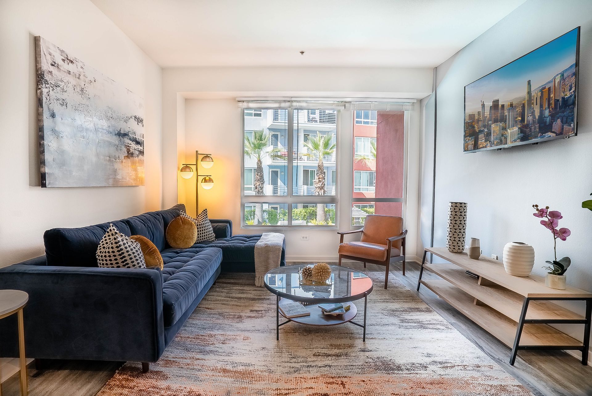 A living room with a couch , chair , coffee table and painting on the wall.