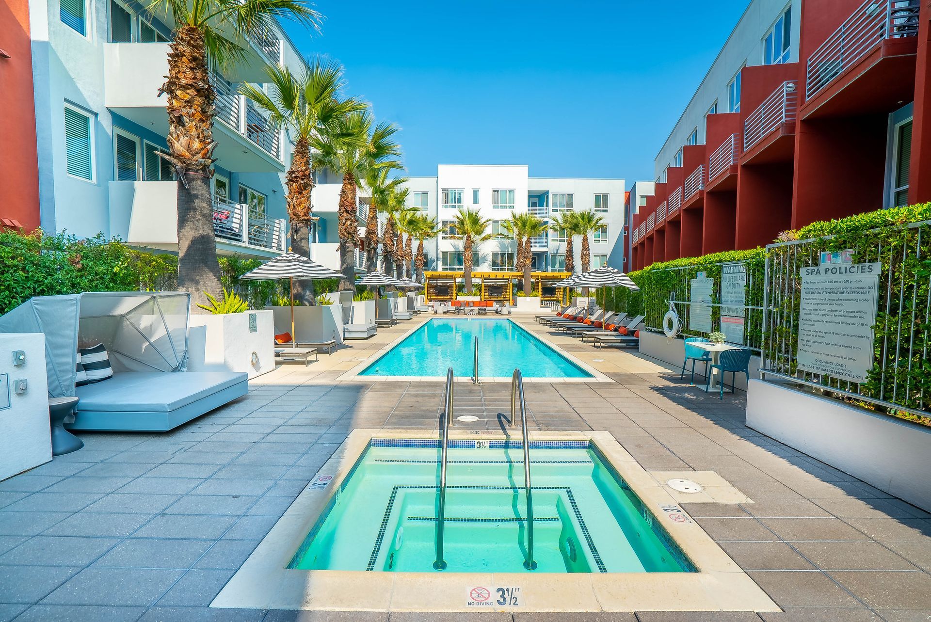 A large swimming pool surrounded by buildings and palm trees