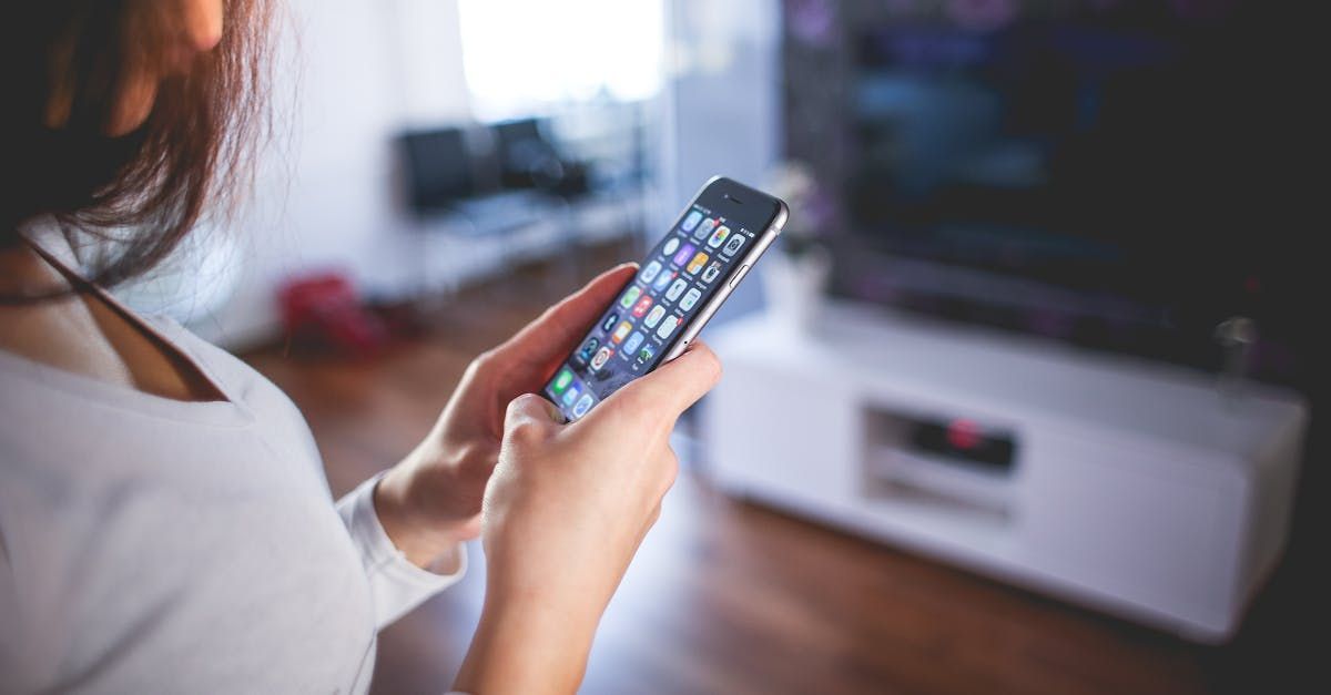 A woman is holding a cell phone in her hands in a living room.